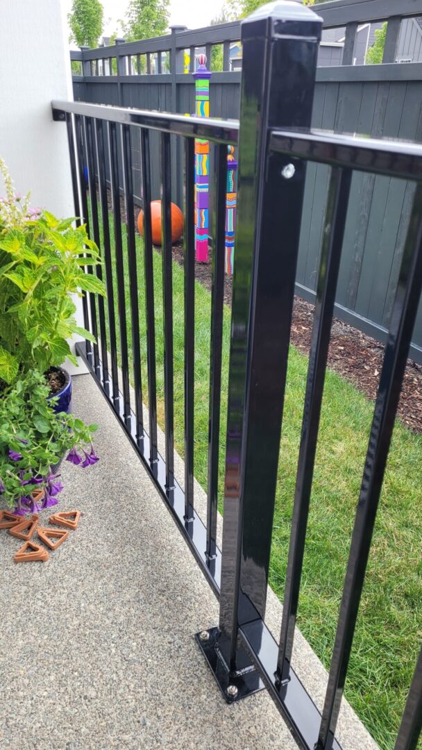 A black fence with a green lawn and flowers