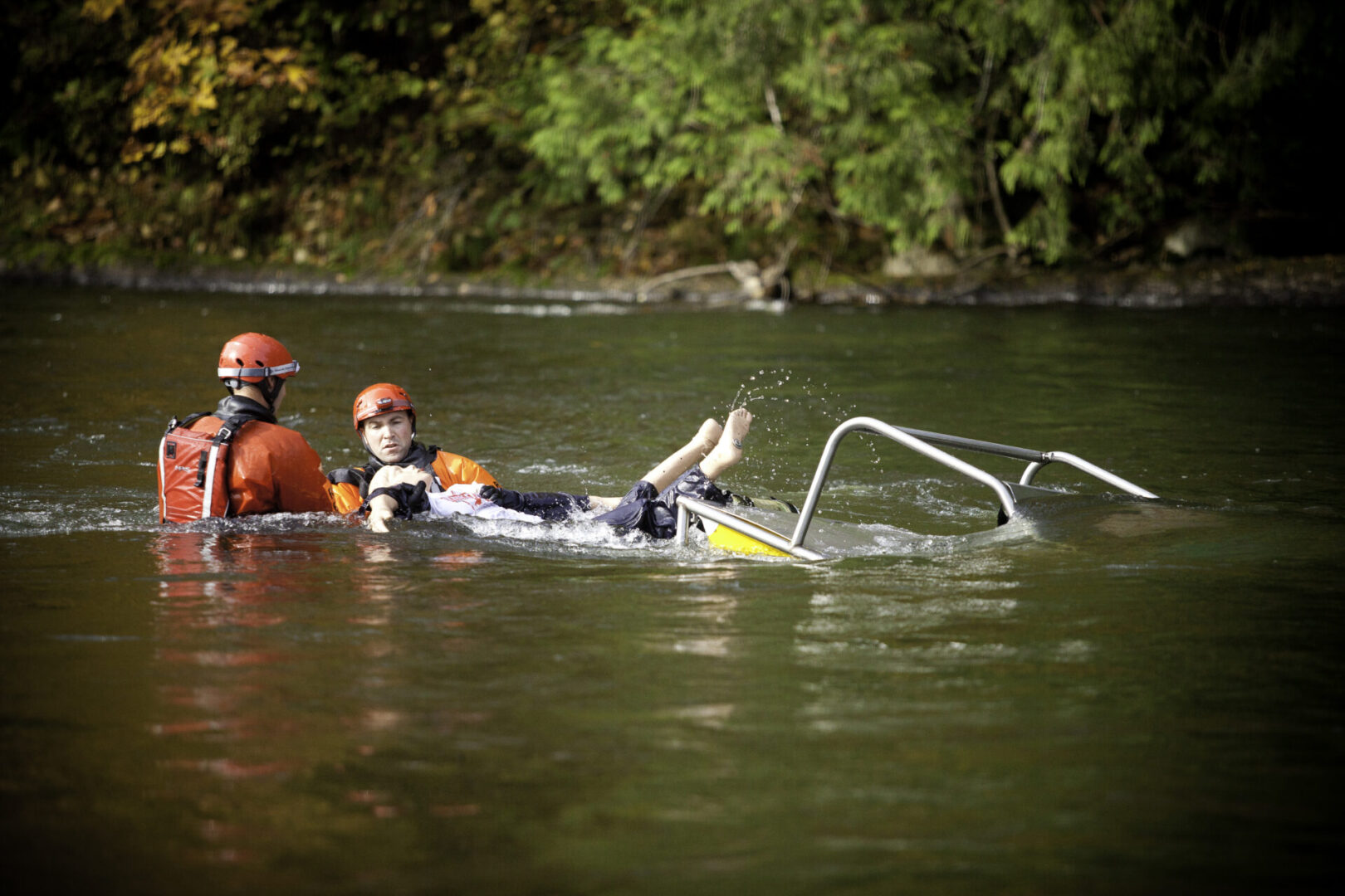 A man and child in the water with a raft.