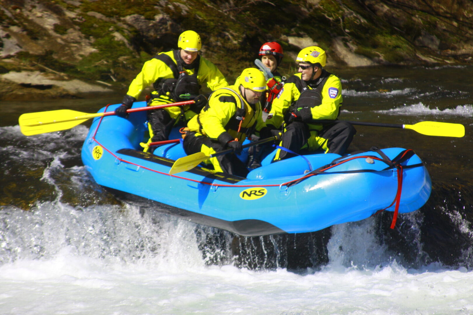 A group of people in yellow jackets on a raft.