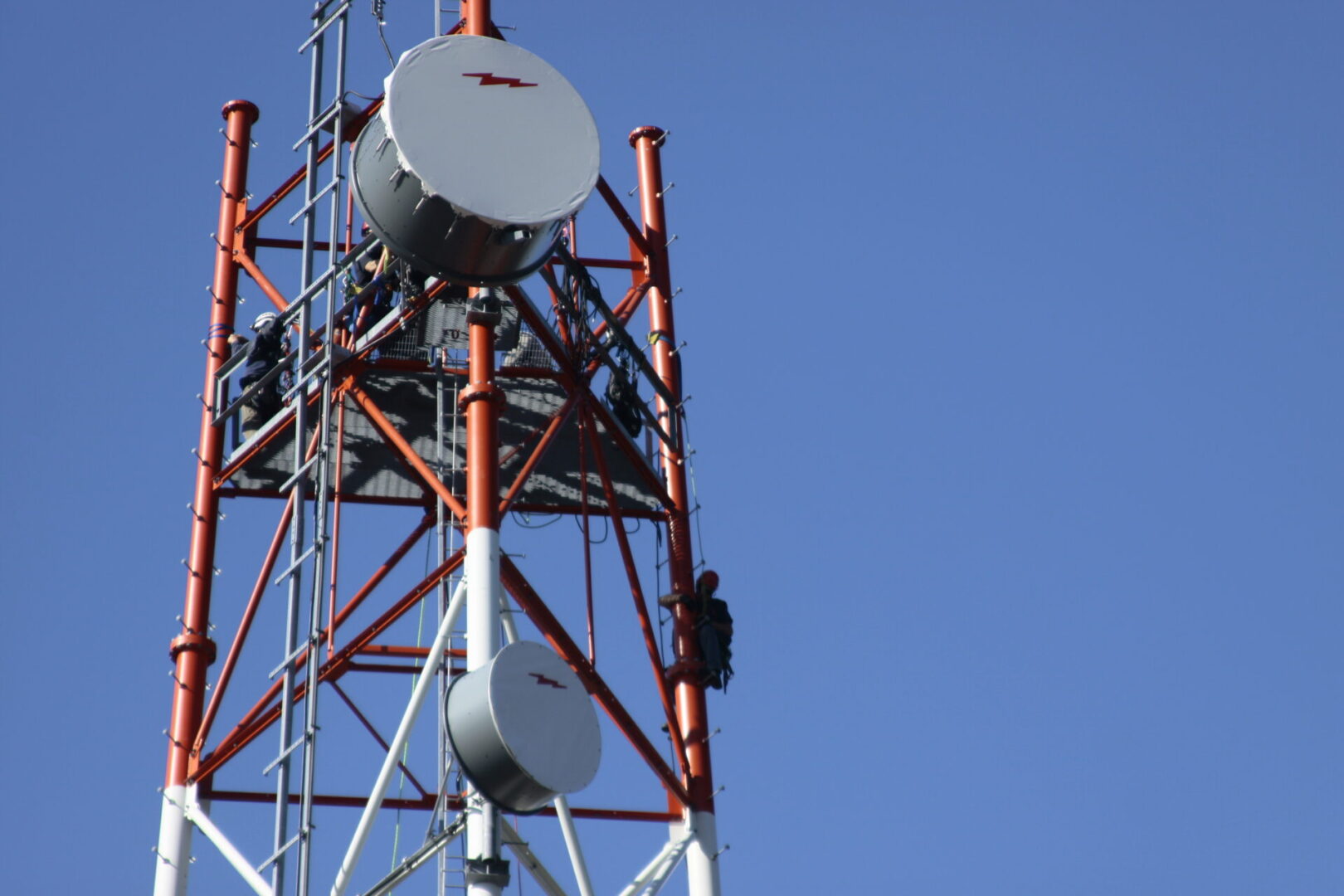 A man standing on top of a tower with two antennas.