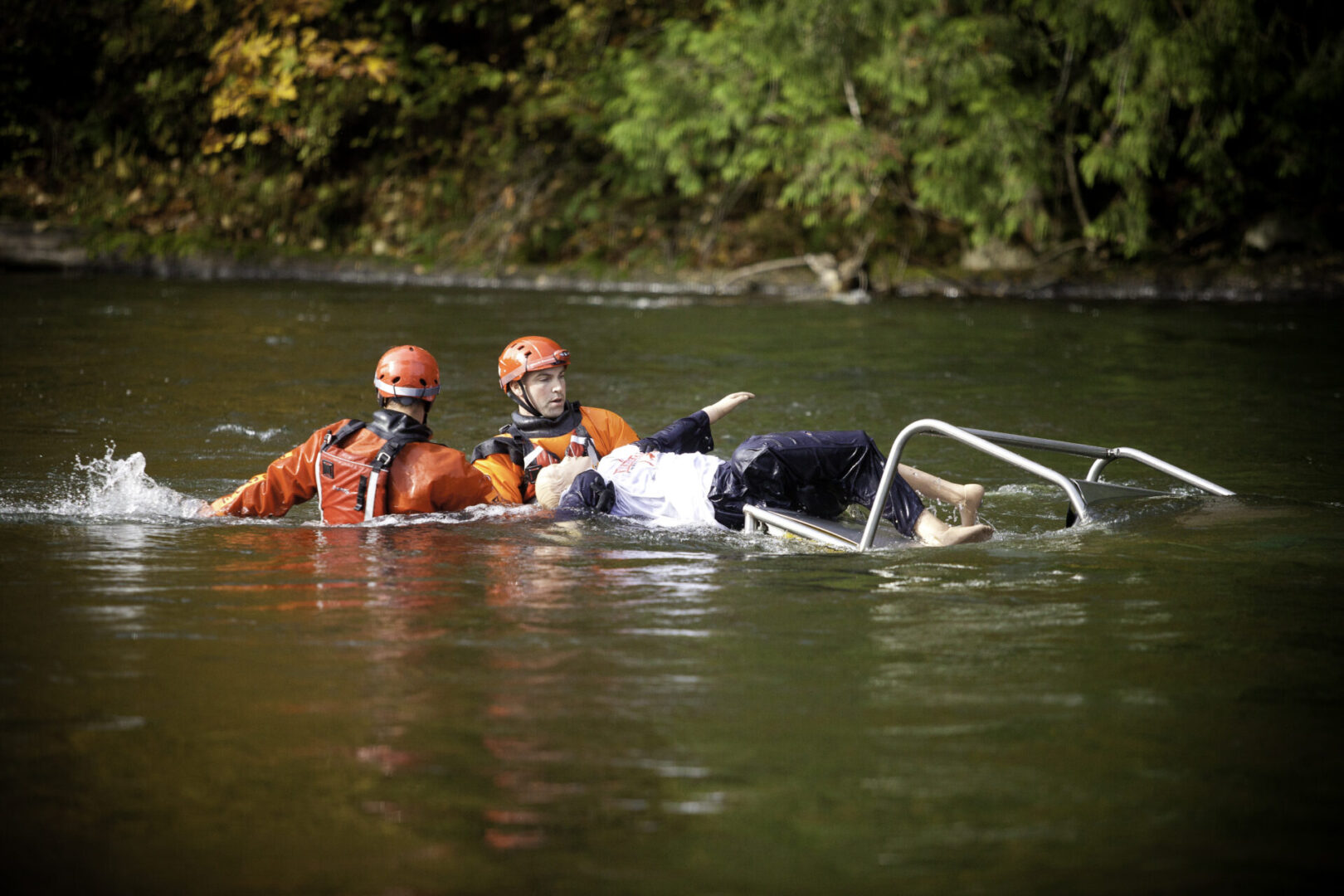 Two people in orange suits are floating on a raft.