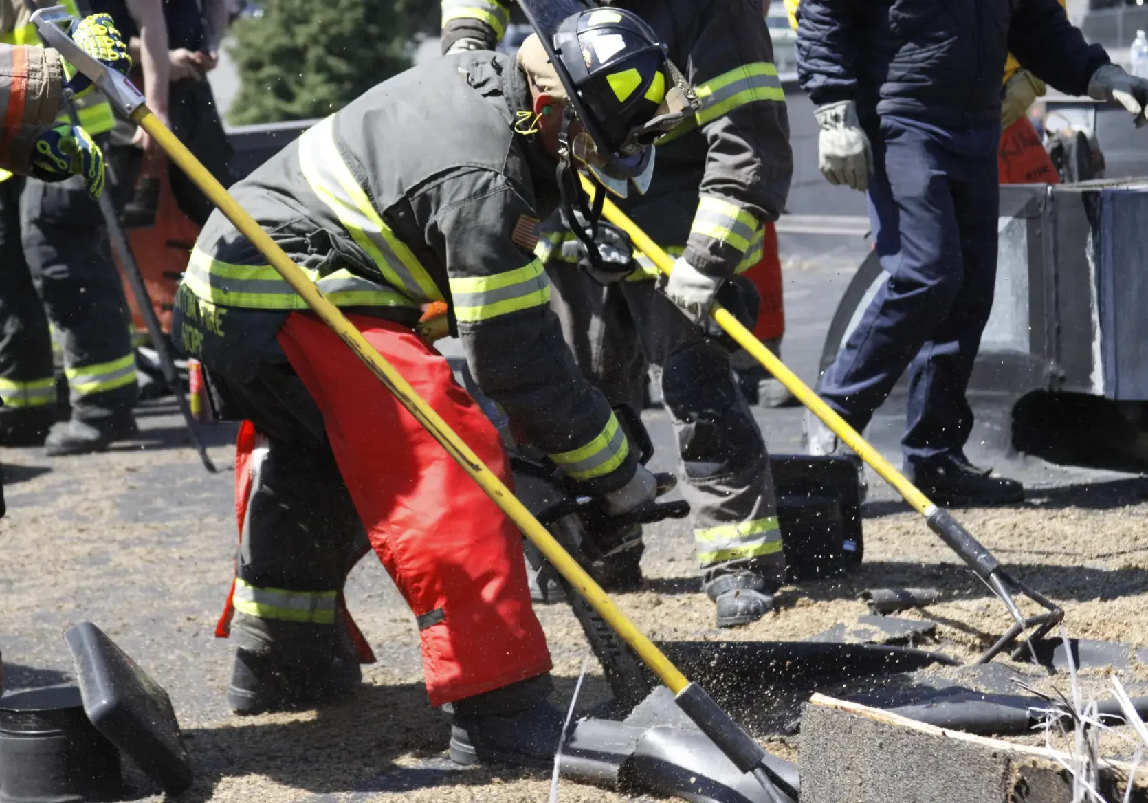 A group of firemen working on the side of a road.